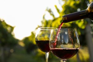 pouring wine into a glass in the middle of vineyards